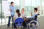 Präsentation an Flipchart vor Leuten von denen einer im Rollstuhl sitzt