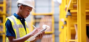 Produktion_Logistik_Junger Mann mit Checkliste in Lagerhalle