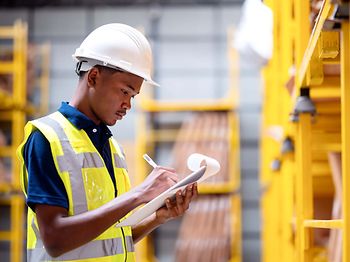 Produktion_Logistik_Junger Mann mit Checkliste in Lagerhalle