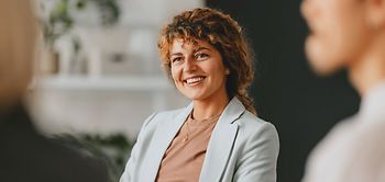Confident businesswoman smiling while interacting with colleagues