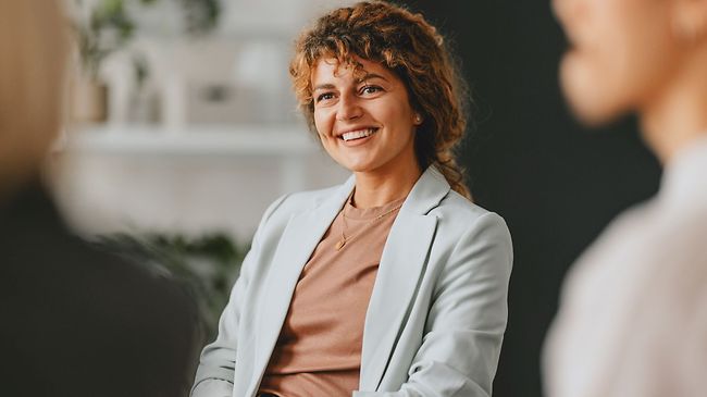 Confident businesswoman smiling while interacting with colleagues