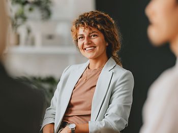 Confident businesswoman smiling while interacting with colleagues