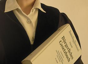 Richterin mit Robe hält bürgerliches Gesetzbuch hoch