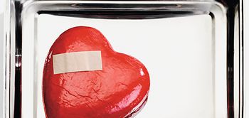 Rotes Herz mit Pflaster liegt in Metallschale