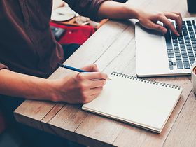 Schreiben auf Block und Laptop