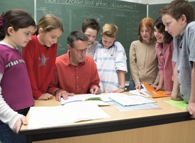 Schueler am Lehrertisch im Klassenzimmer