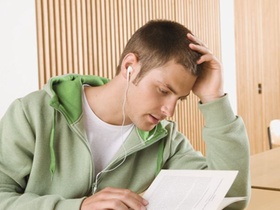 Schueler hoert mit Ohrhoerern Musik und liest ein Buch