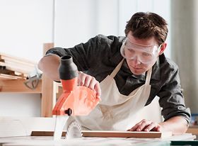 Schutzkleidung tragender Mann an Tischsäge