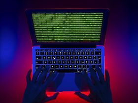 Schwarze Hände tippen auf Laptop mit Binärcodes