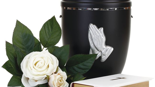 Schwarze Urne mit Rose und Bibel