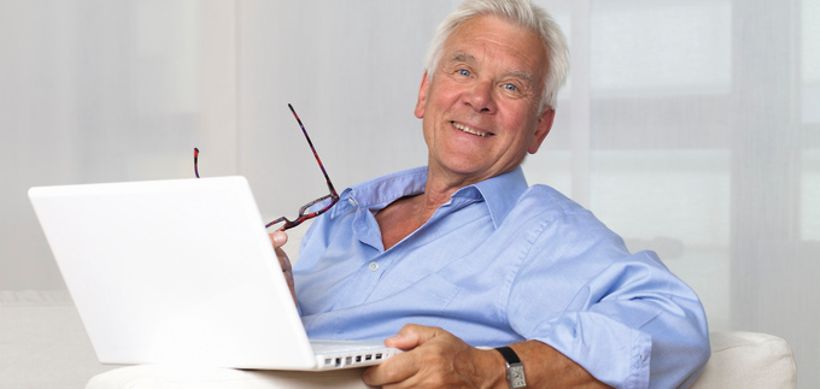 Senior sitzt mit Laptop auf Sofa
