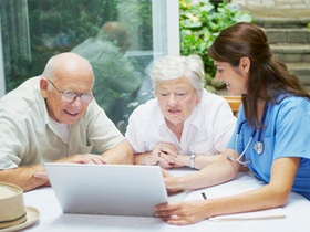 Senioren und Krankenschwester am Laptop Pflege planen