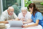 Senioren und Krankenschwester am Laptop Pflege planen