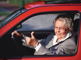 Seniorin am Steuer eines Autos, Gestik Daumen hoch