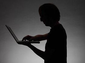 Silhouette einer Person die am Laptop arbeitet