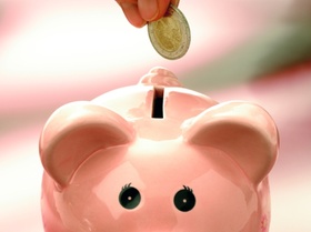 Sparschwein mit Geldmünze und Hand