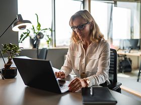 Steuerfachangestellte am Schreibtisch mit Laptop frontalansicht