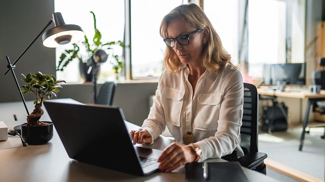Steuerfachangestellte am Schreibtisch mit Laptop frontalansicht