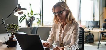 Steuerfachangestellte am Schreibtisch mit Laptop frontalansicht