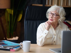 Reflections. Aging gray-haired woman in glasses with bright red lips looking away thoughtfully touch