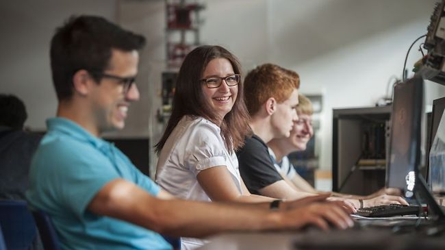 Studenten sitzen glücklich an Computern