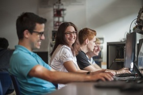 Studenten sitzen glücklich an Computern