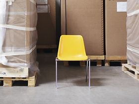 Stuhl steht zwischen Paletten mit Kartons