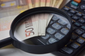 Taschenrechner und 50-Euro-Scheine unter einer Lupe