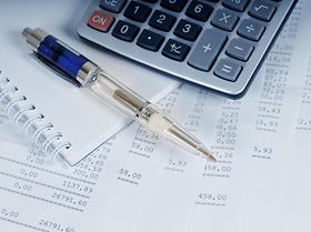 Taschenrechner und Kugelschreiber liegen auf Rechnungen