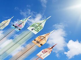 Papierflieger aus Geld steigen in den Himmel