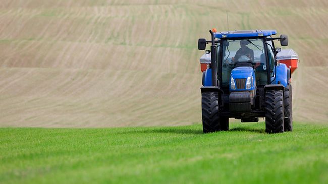 Tractor spreading fertilizer in field