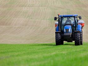 Tractor spreading fertilizer in field