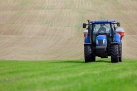 Tractor spreading fertilizer in field