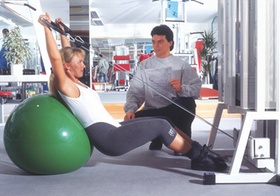 Trainer gibt Frau im Fitnessstudio Anleitung beim Training