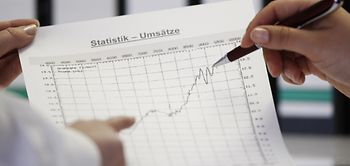 Umsatzstatistik Blatt mit Kurve und zwei Hände
