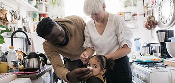 Vater putzt Nase vom Kind in der Küche