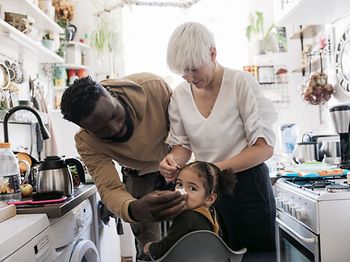 Vater putzt Nase vom Kind in der Küche