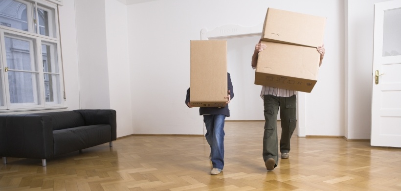 Vater und Sohn tragen Umzugskartons in Wohnung