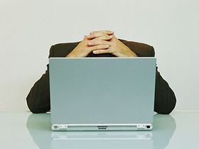 Verzweifelter Mann hinter Laptop