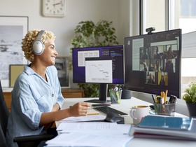 Cheerful businesswoman holding document during video conference with colleagues. Smiling blond Afro