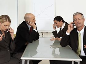 Vier Teammitglieder telefonieren an Tisch