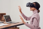 Virtual Reality: Frau trägt vor Laptop VR-Brille