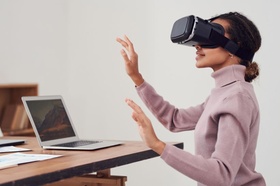 Virtual Reality: Frau trägt vor Laptop VR-Brille