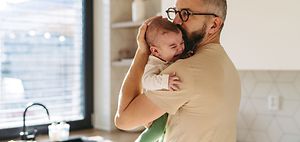 weinendes Baby in dem Arm vom Vater