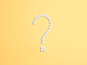 Weißes Fragezeichen aus Tabletten auf gelbem Grund