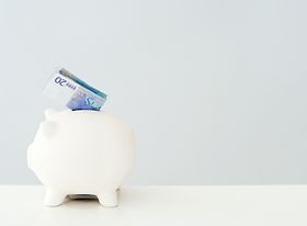 Weißes Sparschwein mit eingestecktem 20 Euro Schein