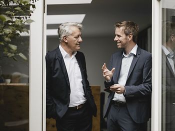 zwei Businessmänner stehen in einer Tür und reden