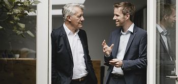 zwei Businessmänner stehen in einer Tür und reden