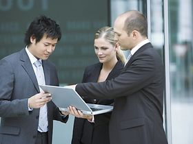 Zwei europäische und ein asiatischer Mitarbeiter mit Laptop