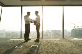 zwei Geschäftsmänner schütteln sich in hellem Büro die Hände